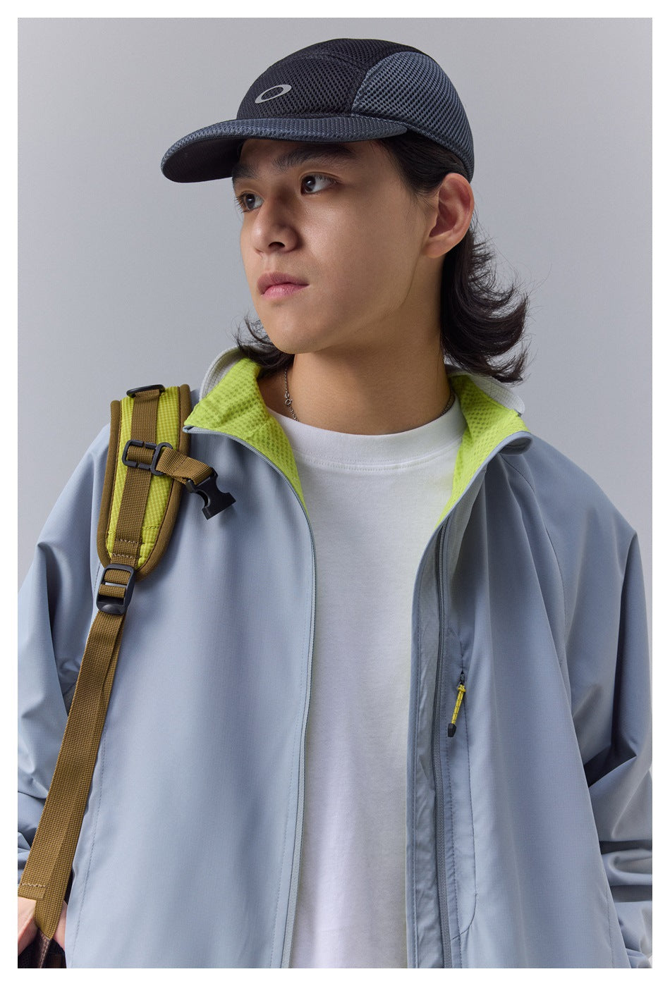 Close-up of a model wearing a blue-gray outdoor jacket with a bright lime inner collar and zip pocket.