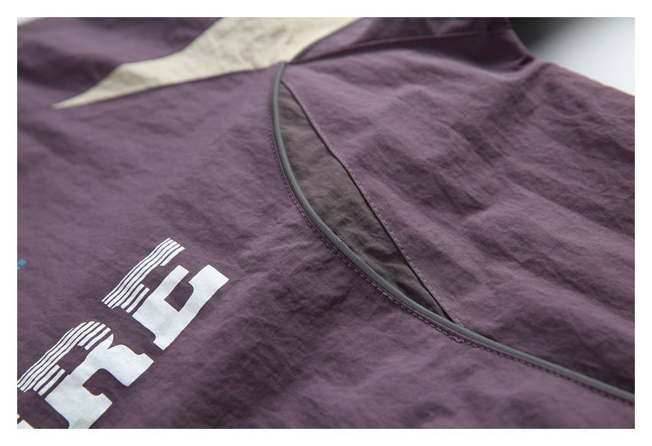 Close-up showing plum fabric, curved gray piping, and part of a white printed graphic.