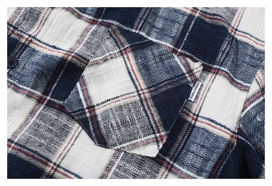 Close-up of a navy, white, gray, and red plaid shirt with a small fabric label.