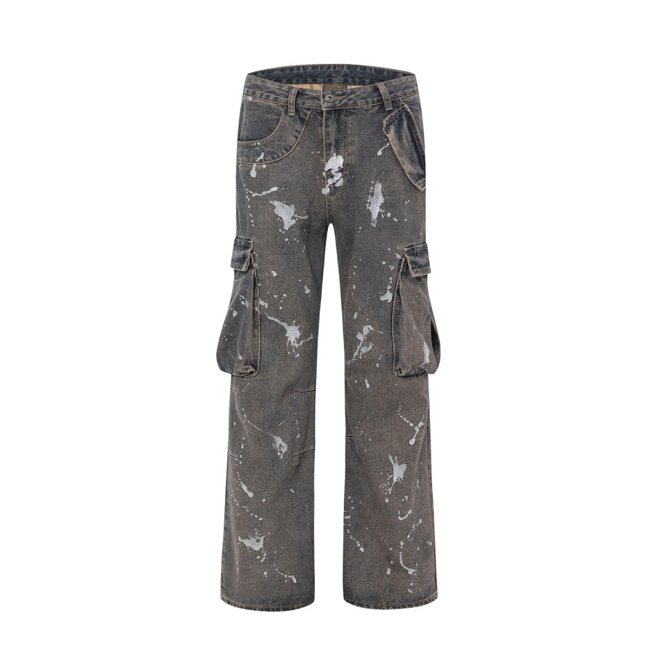 Front view of faded gray-brown wide-leg cargo jeans with silver paint splatters and large side flap pockets