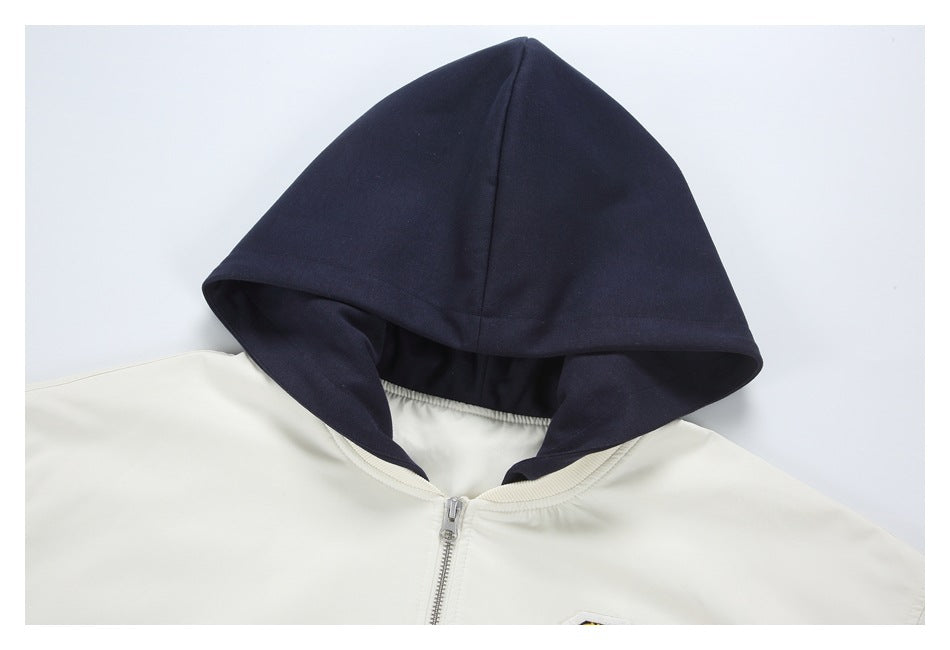 Close-up of a cream zip jacket with a large dark navy hood and ribbed neckline.