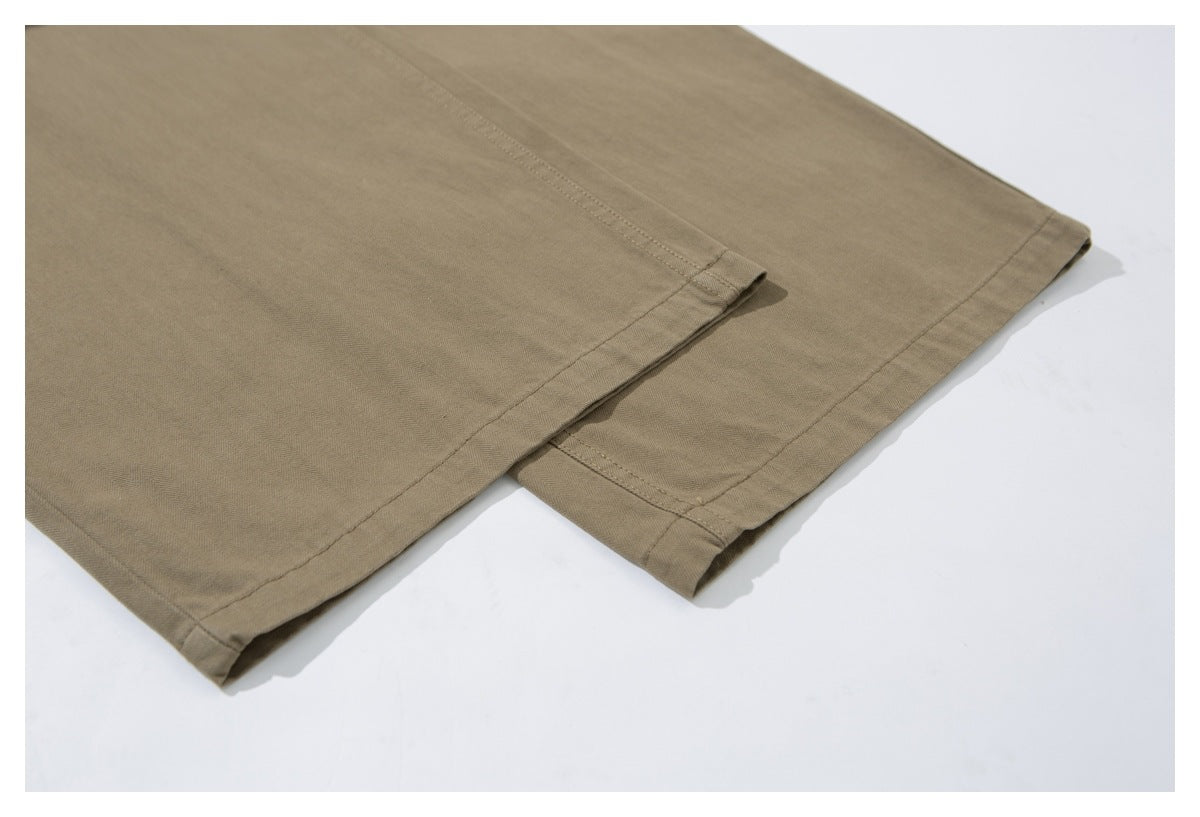 Close-up of the stitched hems on khaki trousers laid flat.