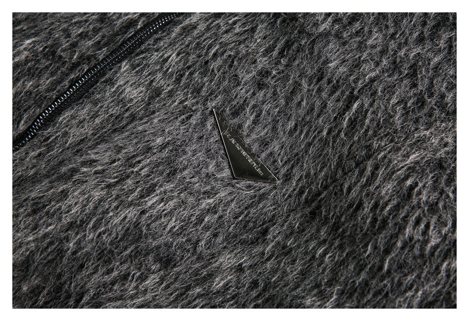 Close-up of a triangular black plaque on the dark gray fuzzy jacket.