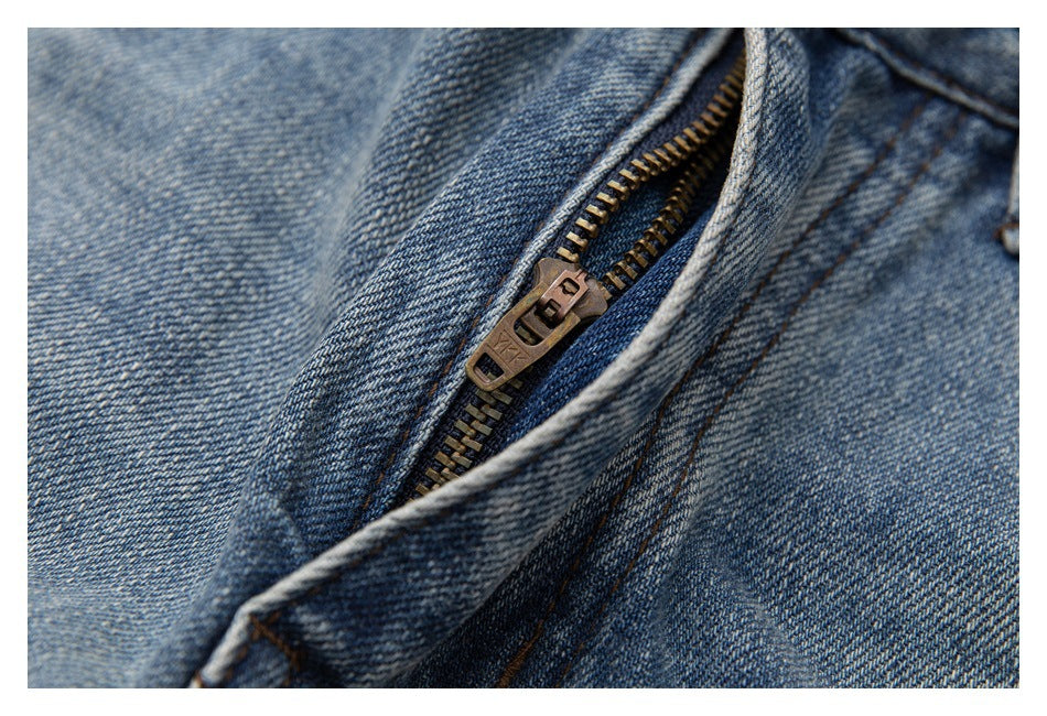 Close-up of a brass zipper and seam on blue denim jeans.