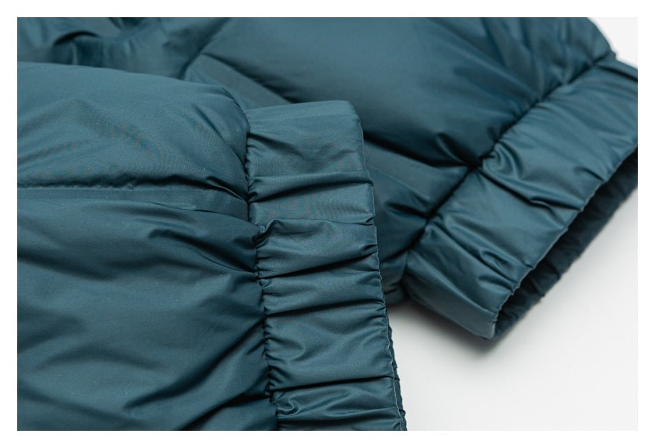 Close-up of a teal padded jacket's gathered sleeve cuff and quilted sections.