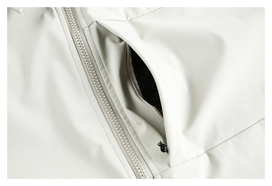 Close-up of an ivory garment's open pocket, showing black mesh lining beside the front zipper.