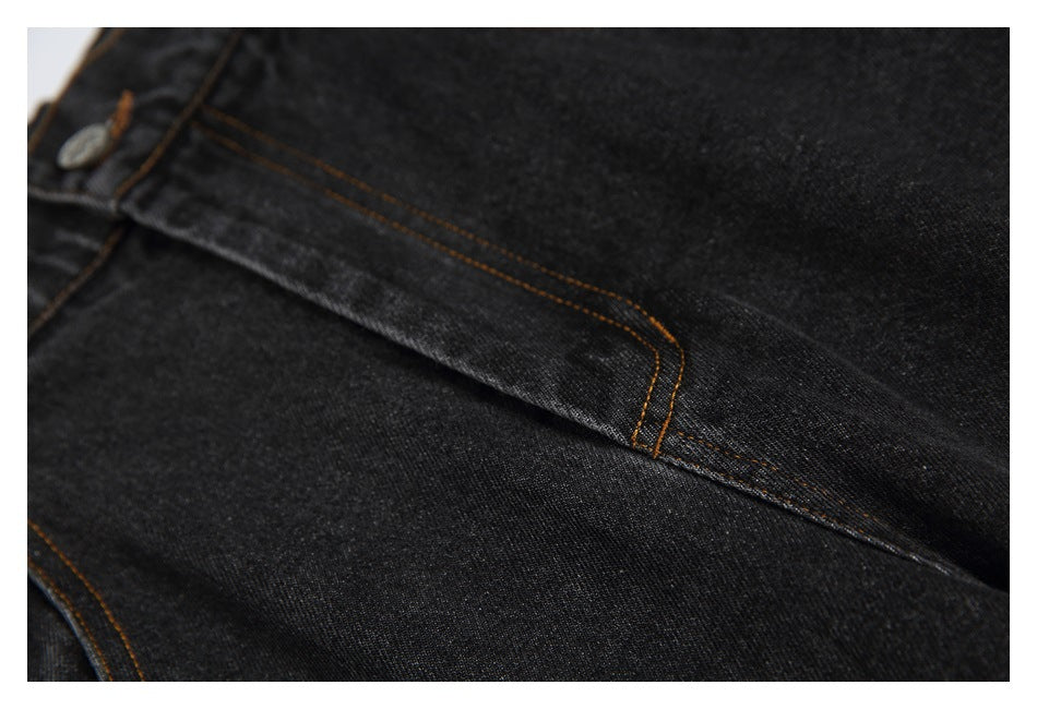 Close-up of black jeans showing a double-stitched seam and a partial metal button.