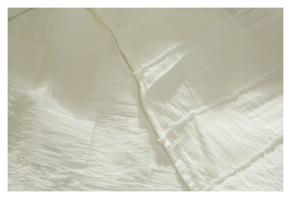 Close-up of ivory fabric showing alternating woven textures and raised seam lines.