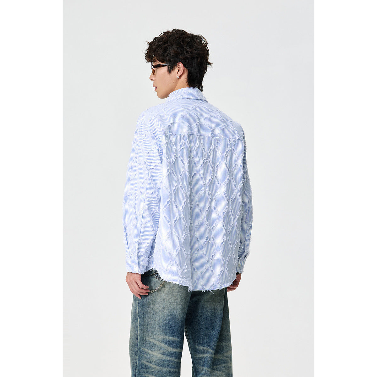 Back view of a model wearing a pale blue pinstriped shirt with raised white diamond detailing.