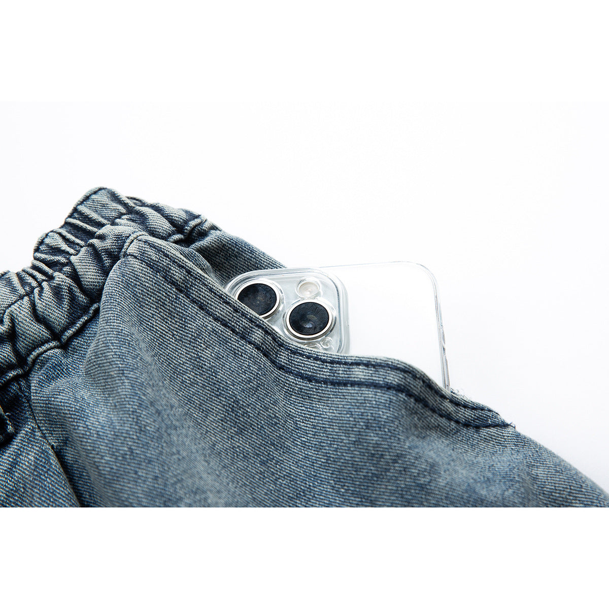 Blue denim shorts pocket shown holding a smartphone in a clear case.
