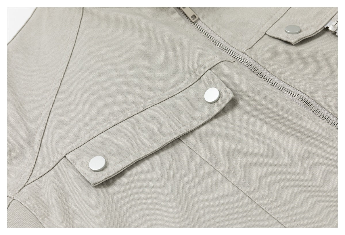 Close-up of a light beige jacket's diagonal zipper and snap-button front strap.