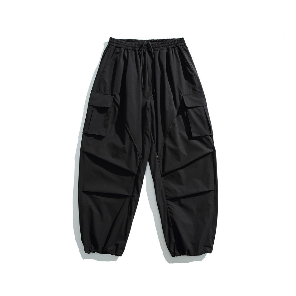 Black wide-leg cargo pants with drawstring waist, flap thigh pockets and gathered hems, flat lay