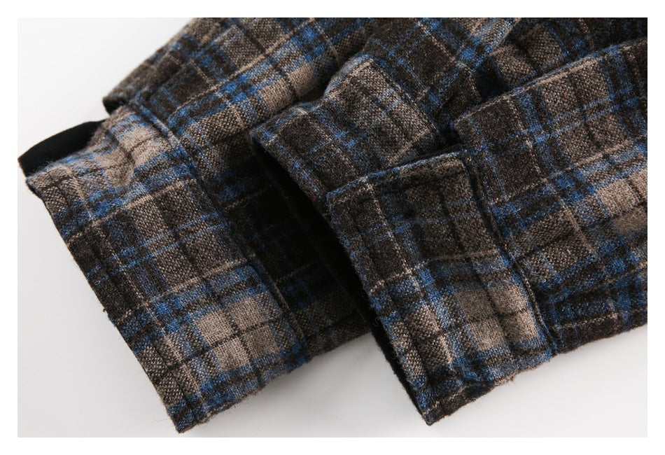 Close-up of a folded opening and stitched edge on brown, charcoal, and blue plaid fabric.
