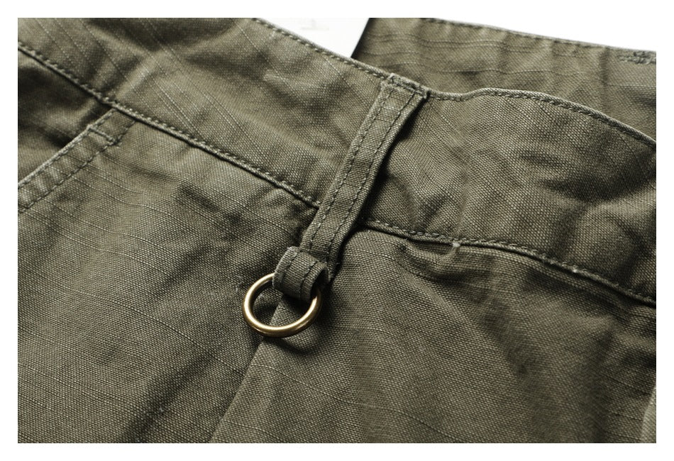 Close-up of an olive waistband belt loop with a brass-colored ring attachment.