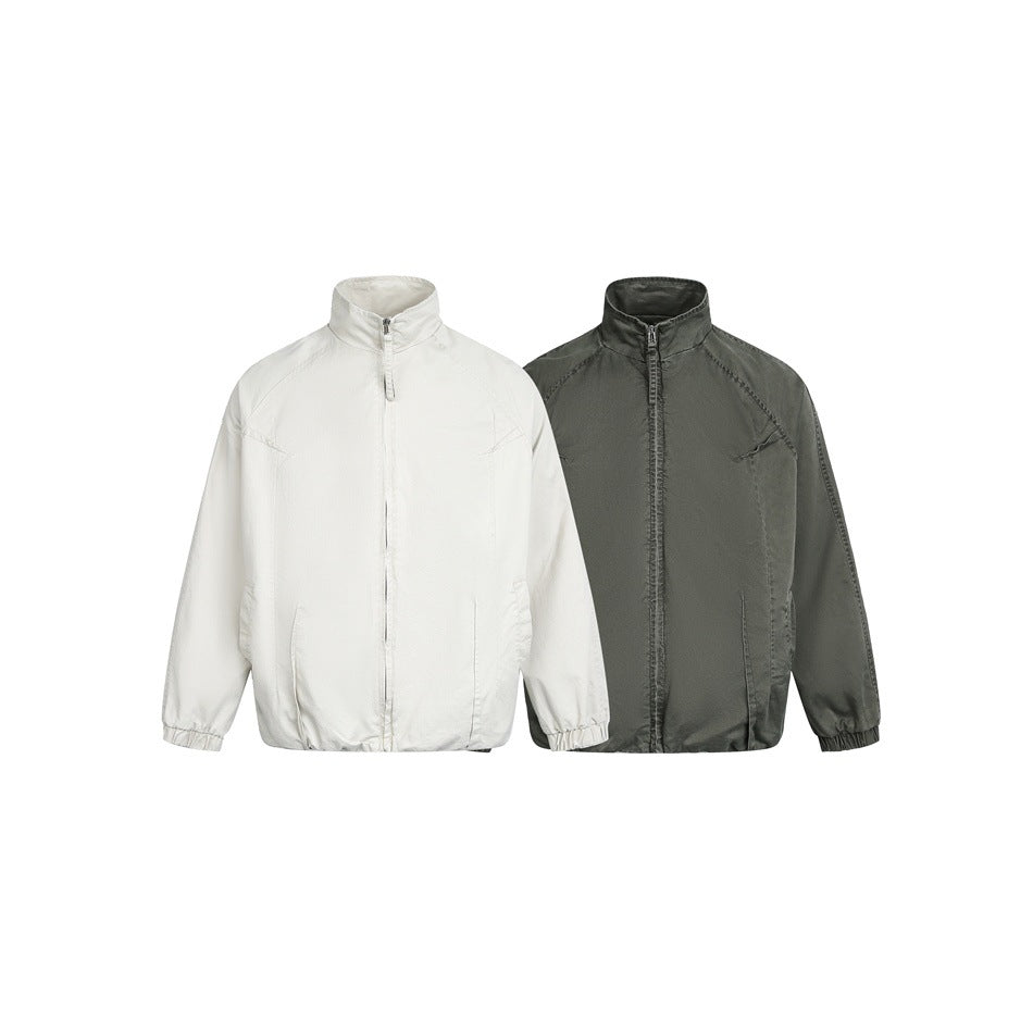 Two front-view zip-up jackets on white, one ivory and one dark olive, with stand collars and elastic cuffs.