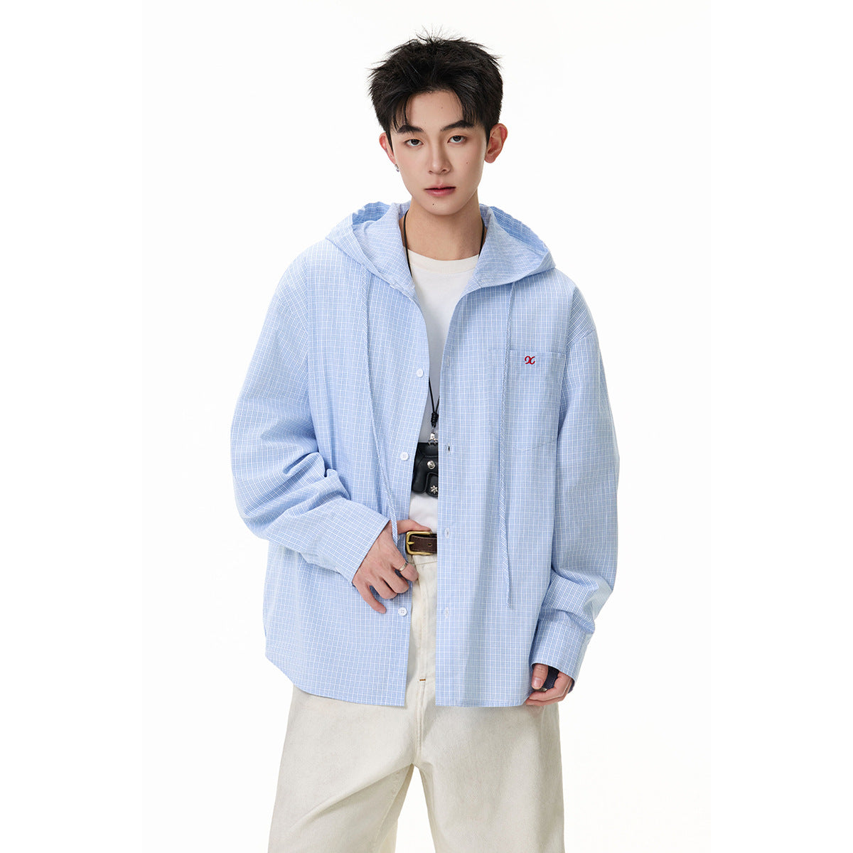 Front view of a model in an oversized light blue checked hooded button-up shirt with cream trousers.