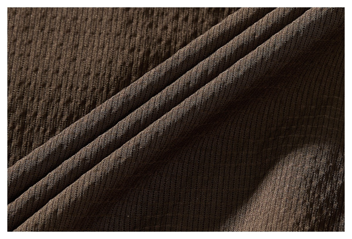 Macro view of the dark brown jacket's textured fabric, shown in folded layers.