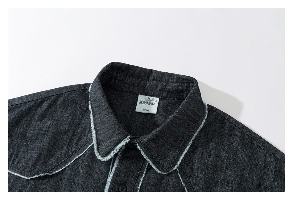 Close-up of a charcoal denim shirt collar with pale frayed-edge stitching and a visible neck label.