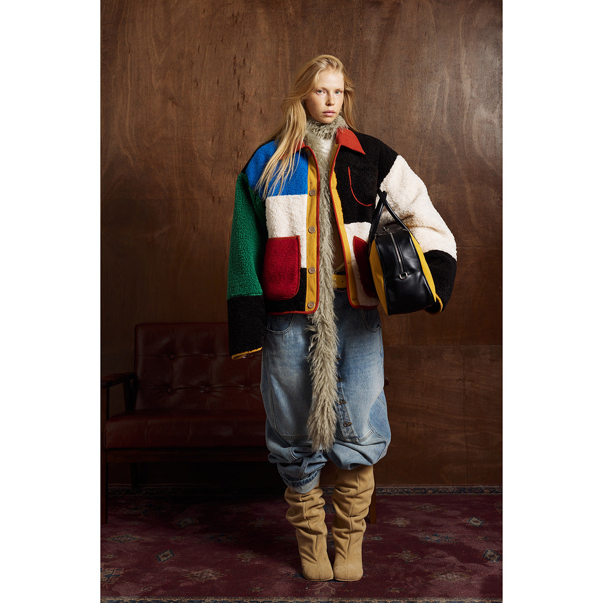 Full-length model wearing a color-block jacket with red pockets, baggy jeans and tan boots; front view.
