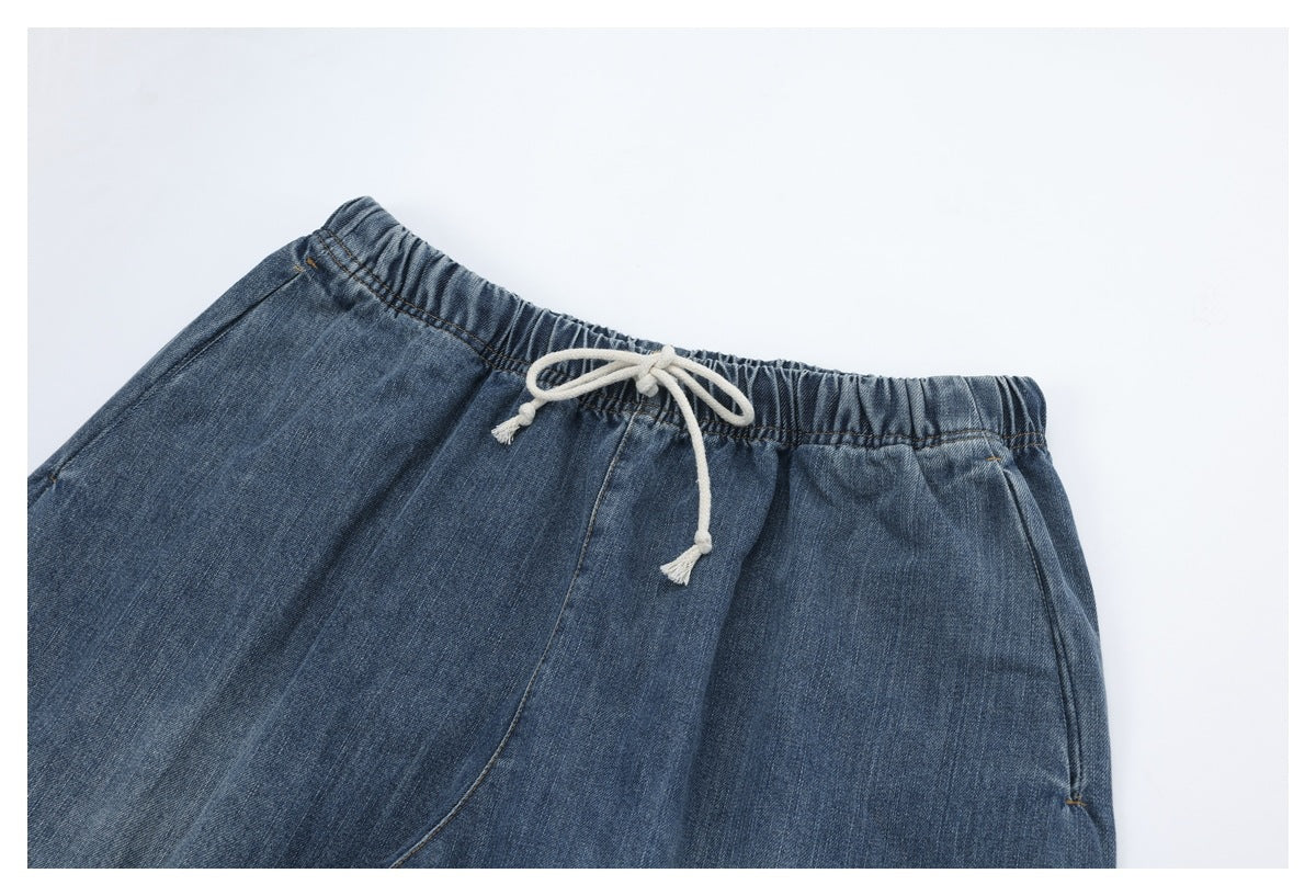 Close-up of blue denim pants showing an elastic waist and cream drawstring.