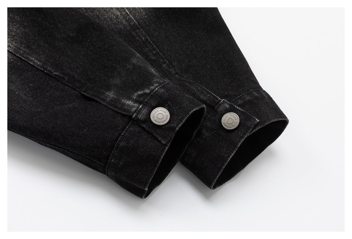 Close-up of black denim jacket cuffs with silver buttons and stitched seams.