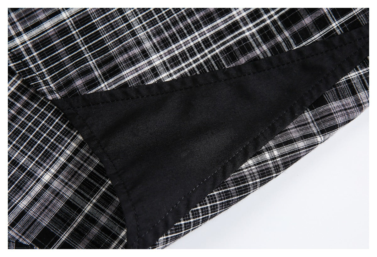 Close-up of black-and-gray plaid garment fabric with a broad black facing and stitched edge.