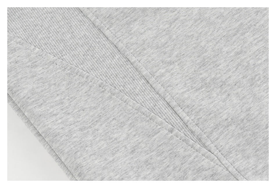 Close-up of heather-gray garment fabric with a ribbed seam and stitching.