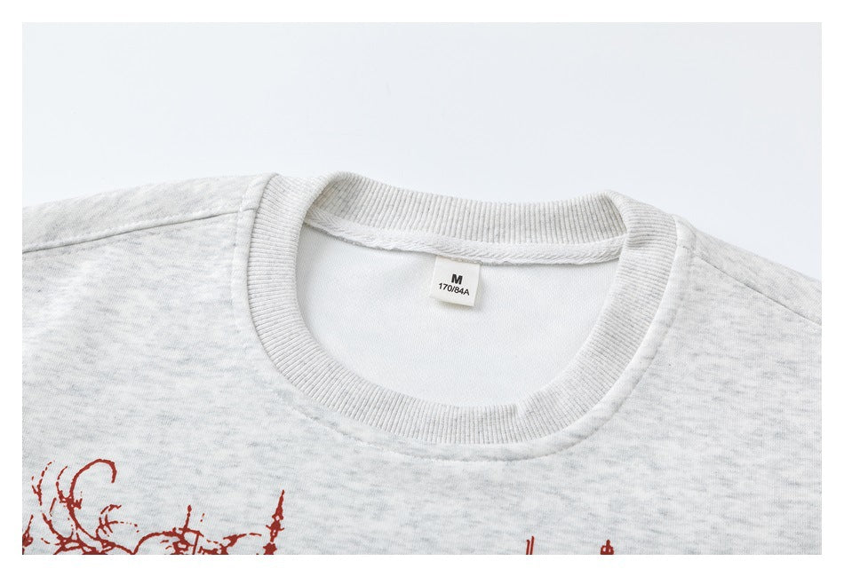 Close-up of a light heather-gray sweatshirt's ribbed crew neck and M size label, with a small portion of red print below.