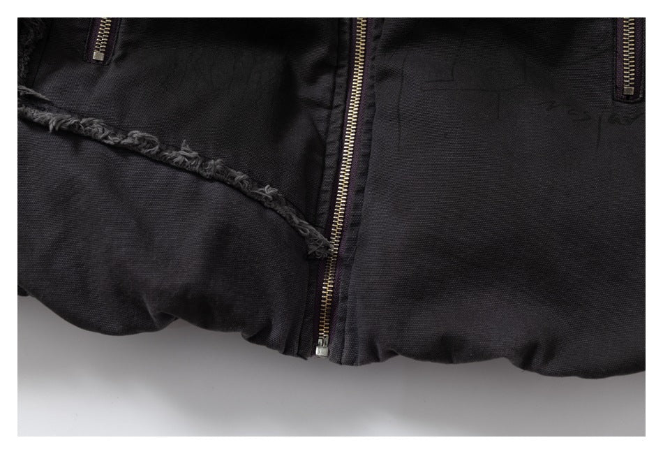 Close-up of the lower front of a black jacket, showing the central zipper and frayed trim.