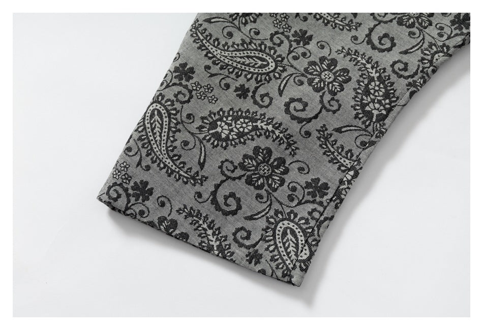 Close-up of a finished edge on gray fabric with an all-over black floral and paisley print.