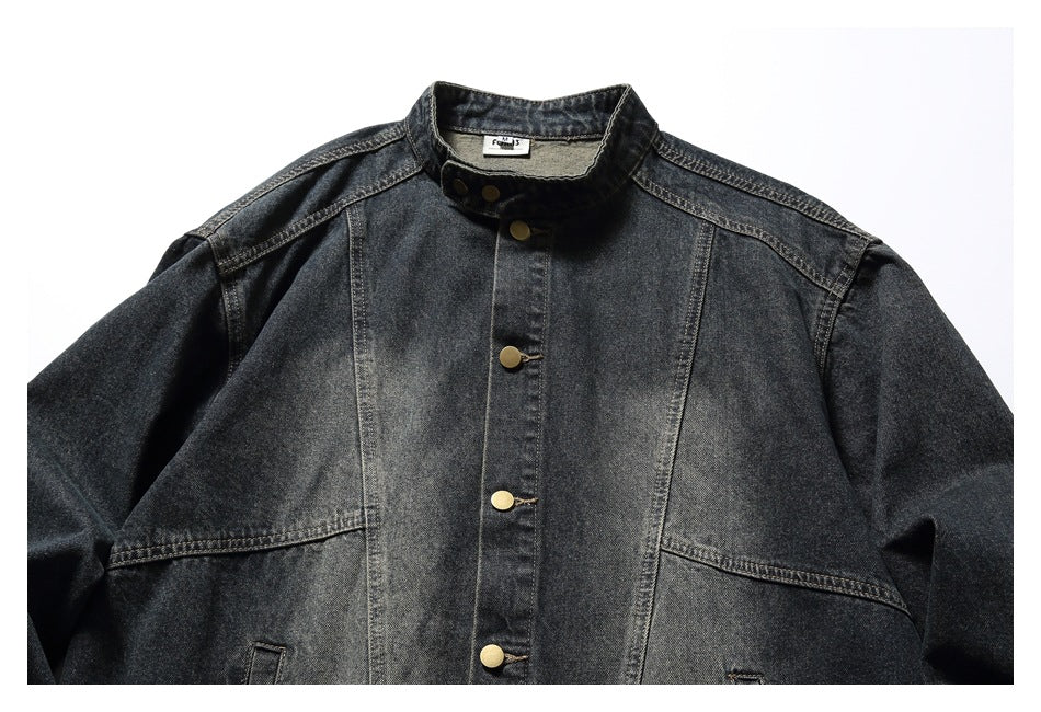 Front view of a dark charcoal denim jacket with a stand collar, brass-tone snap buttons, and contrast seams.