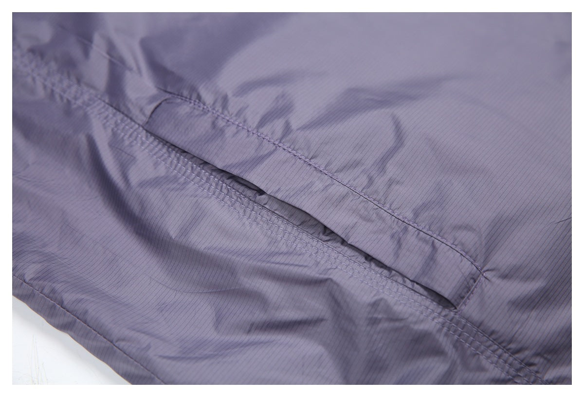 Close-up of a stitched horizontal pocket opening on the vest's smooth lavender-gray fabric.