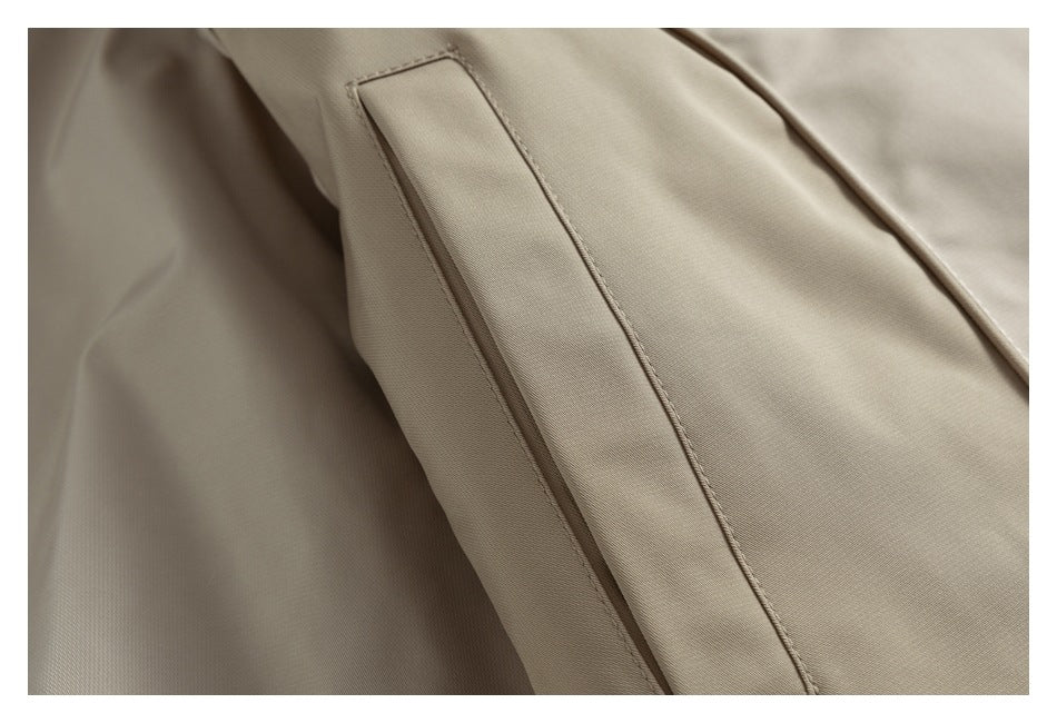 Close-up of a beige jacket's stitched sleeve tab and adjacent panel seam.