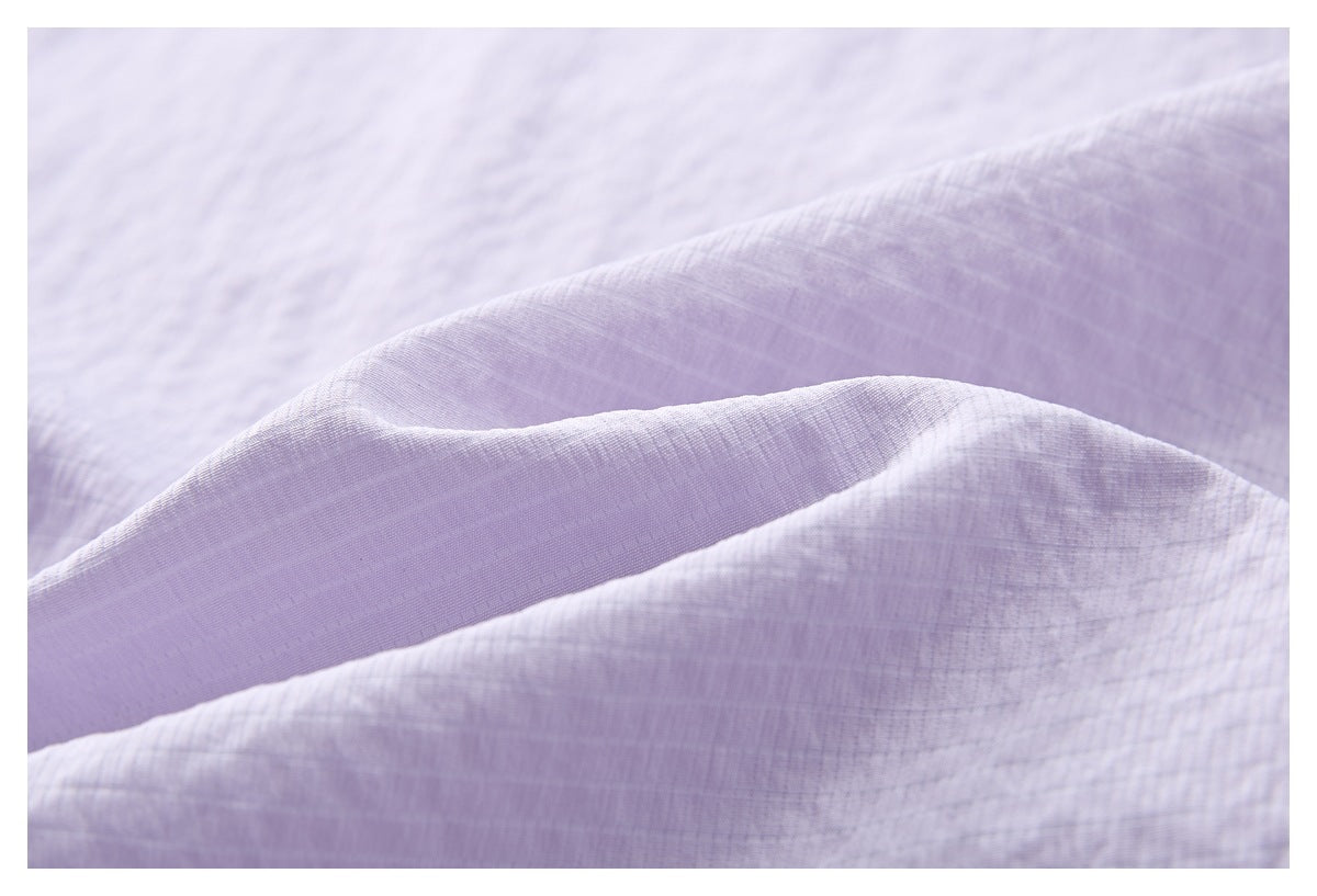 Macro view of the pale lilac top's lightly textured fabric and folded edge.