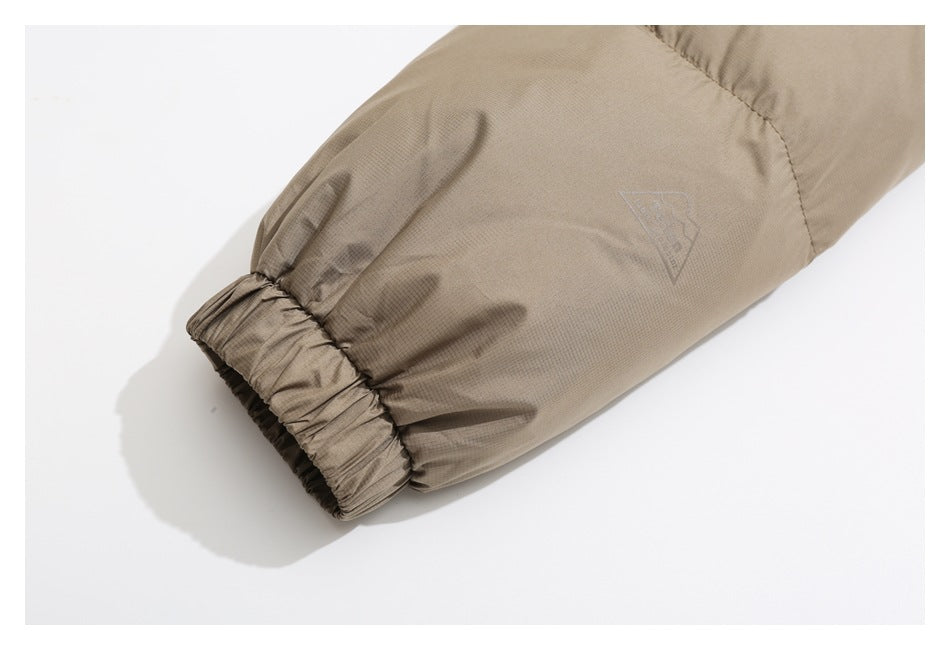 Close-up of a taupe jacket sleeve ending in an elastic cuff, with a small tonal emblem.