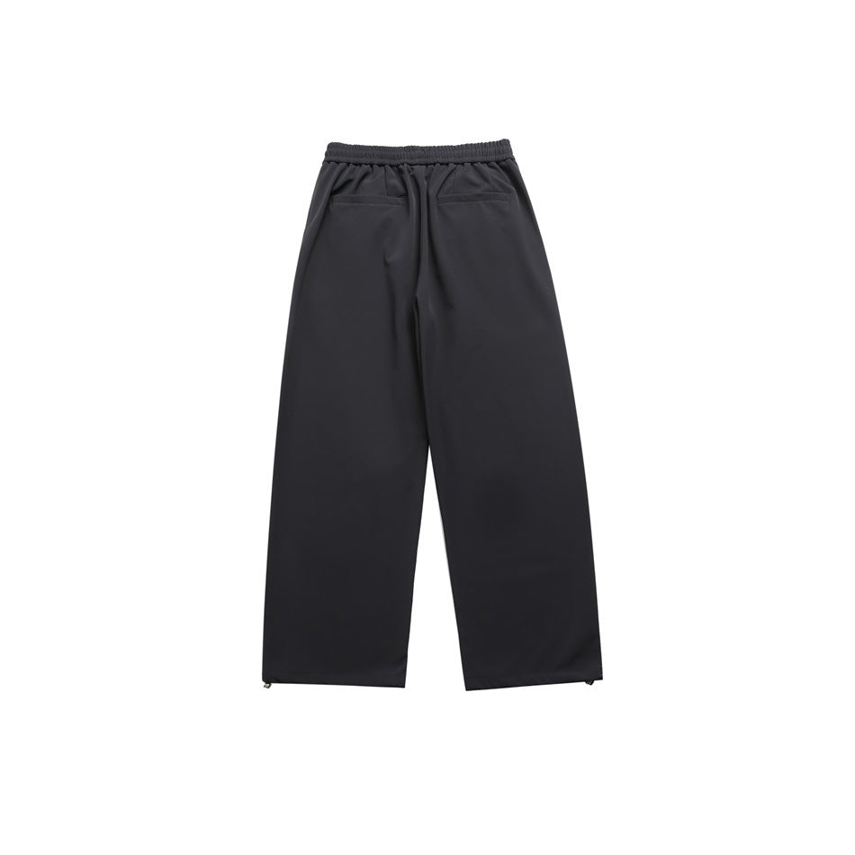 Dark charcoal wide-leg pants back view with elastic waistband, two back welt pockets and hem toggles