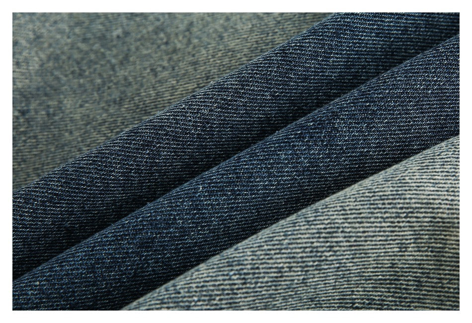 Close-up of dark blue denim fabric folded diagonally, showing its woven texture.