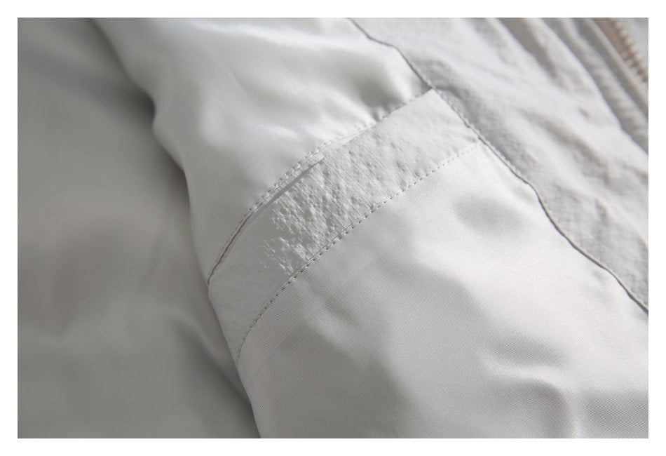Close-up of a light gray jacket sleeve seam and textured fabric panel.