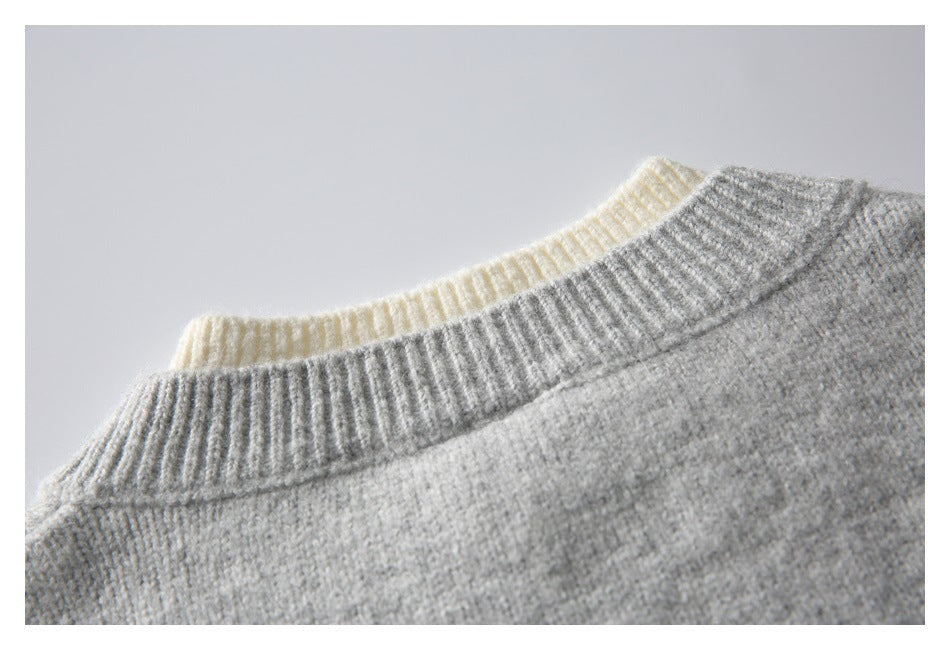 Close-up of a light gray knit sweater neckline with a ribbed collar and a cream layer peeking behind it.