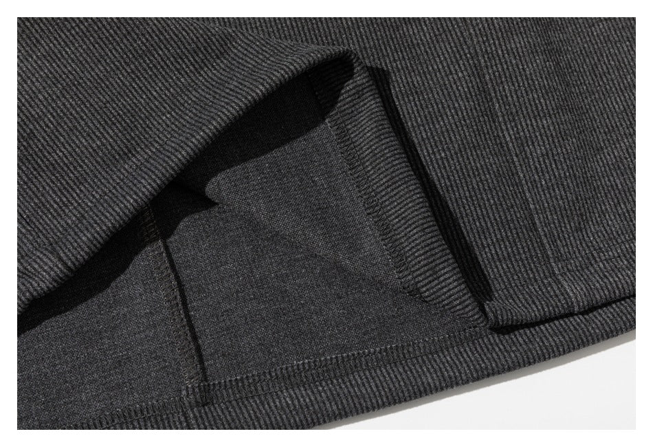 Close-up of a dark gray ribbed garment interior showing an overlocked seam and stitched hem.