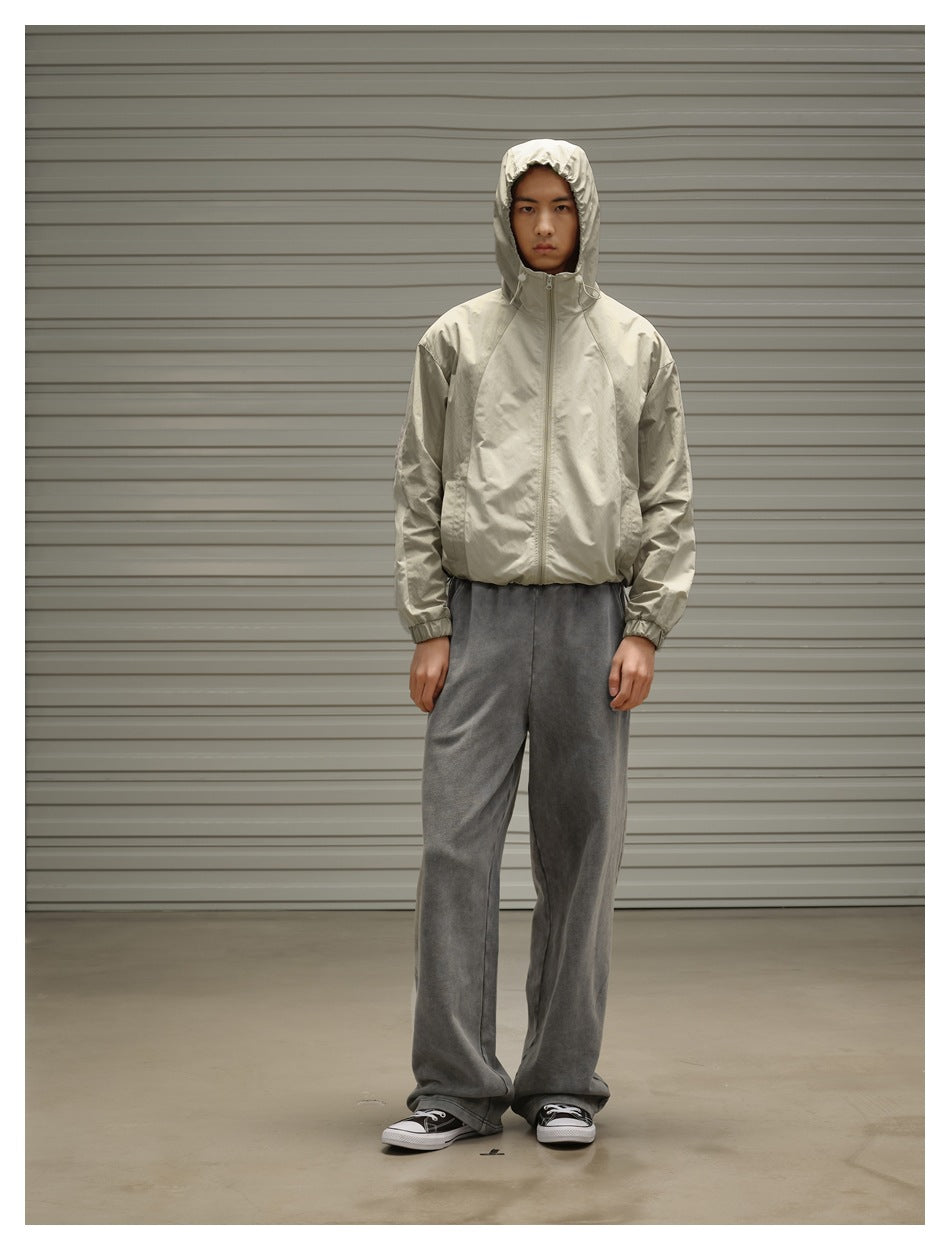 Model wearing a light beige hooded zip jacket with loose gray sweatpants and sneakers.