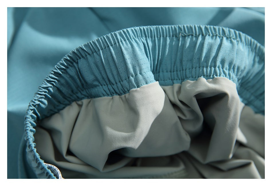 Close-up of gathered turquoise elastic waistband joined to pale gray-green fabric.