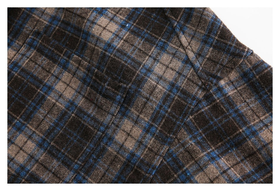 Close-up of brown, charcoal, and blue plaid fabric with a curved stitched seam.
