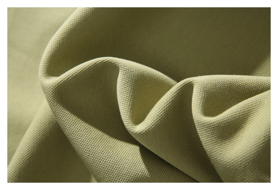 Extreme close-up of the muted olive hoodie’s textured knit fabric folded into soft ridges.