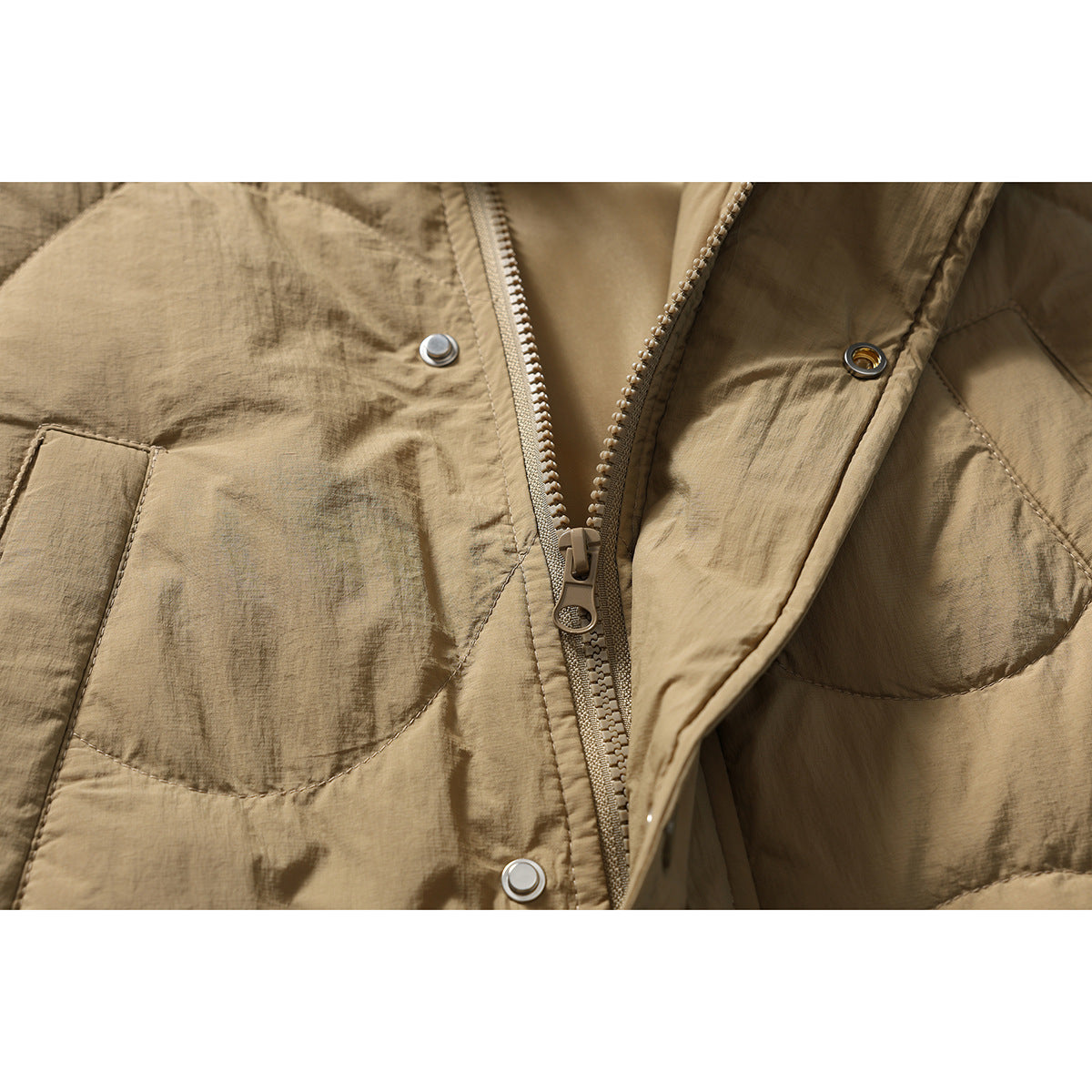 Close-up of the tan vest’s zipper, snap fasteners and quilted front panels.