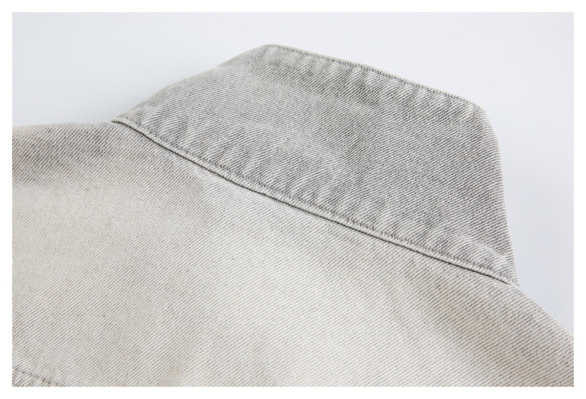 Close-up of a curved stitched yoke seam on pale gray washed denim.