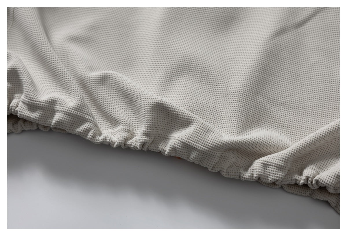 Close-up of the gathered elastic hem on a pale gray waffle-knit garment.