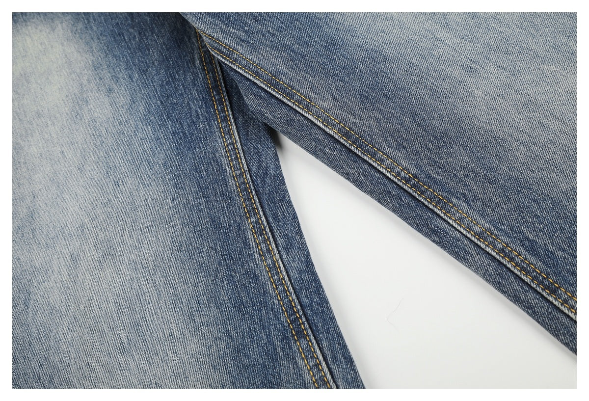Close-up of faded blue denim with golden contrast stitching along a seam.