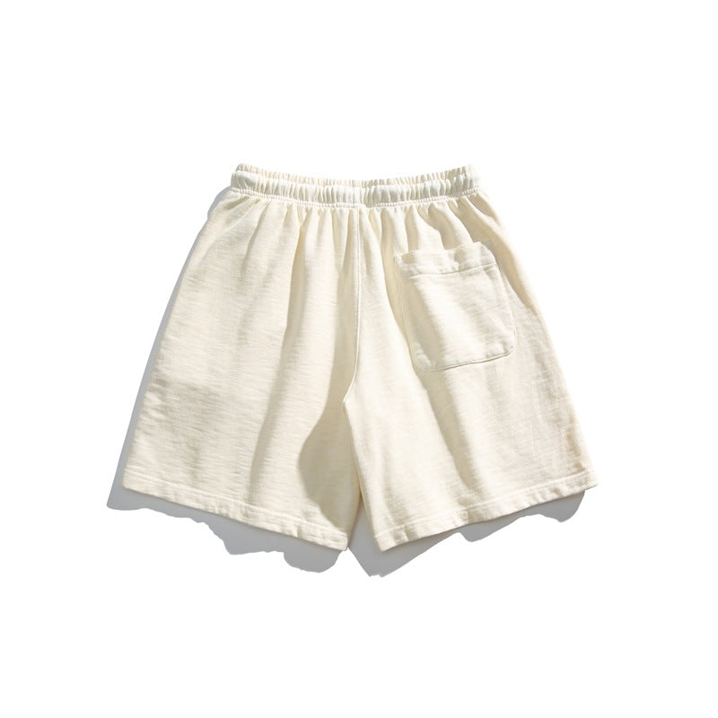 Back view of cream shorts with an elastic waistband and a single patch pocket.