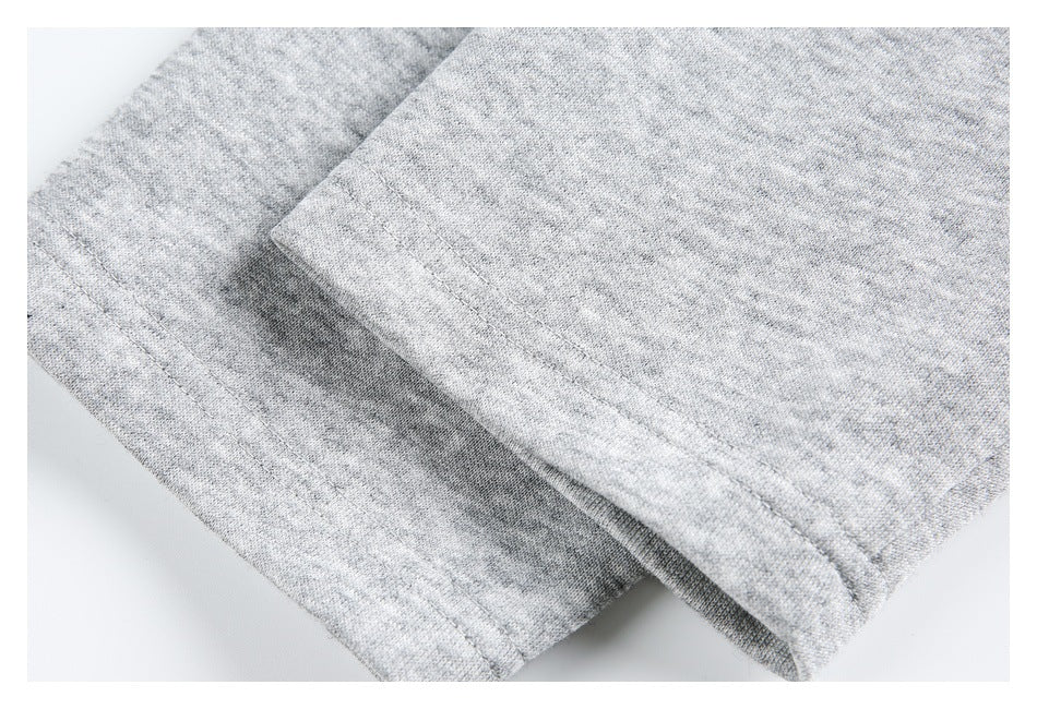 Close-up of overlapping light gray garment edges with parallel stitching.